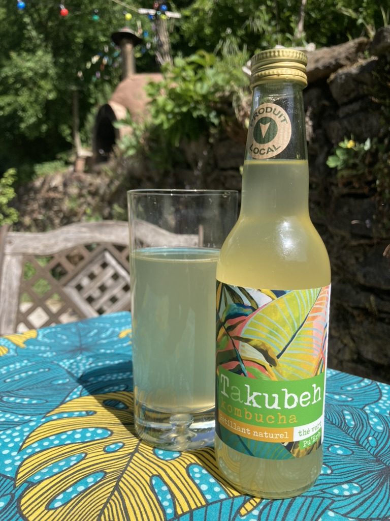 Un verre avec la bouteille de Kombucha de Takubeh